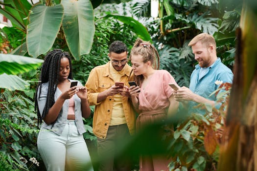 A group of young adults using smartphones in a lush outdoor setting, enjoying leisure and technology together.